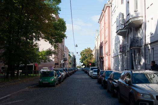 Peaceful urban street lined with cars and residential buildings on a sunny day.