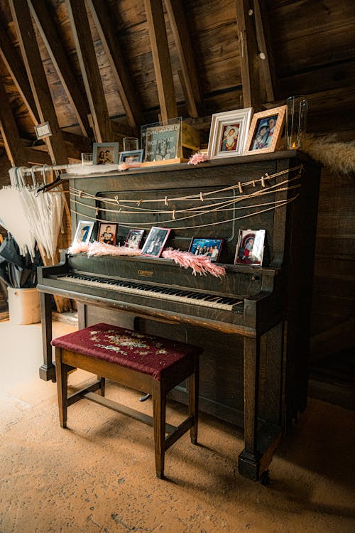 A Vintage Piano with Framed Pictures on It 