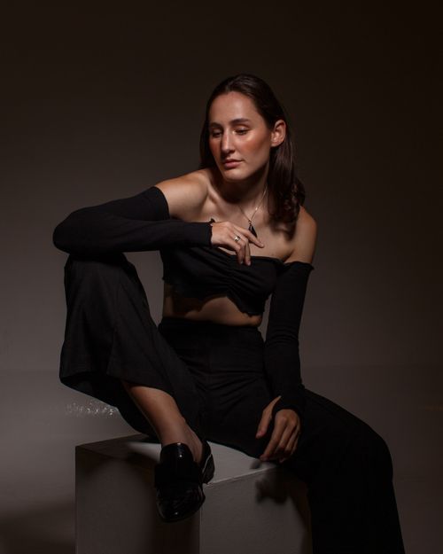 Free Stylish young woman posing in a studio, showcasing modern fashion with a moody ambiance. Stock Photo