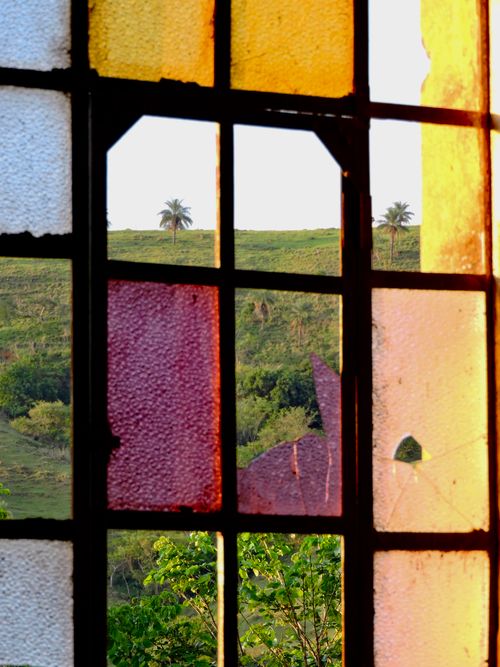 Free A broken stained glass window frames a lush tropical view in Itapira, Brazil. Stock Photo
