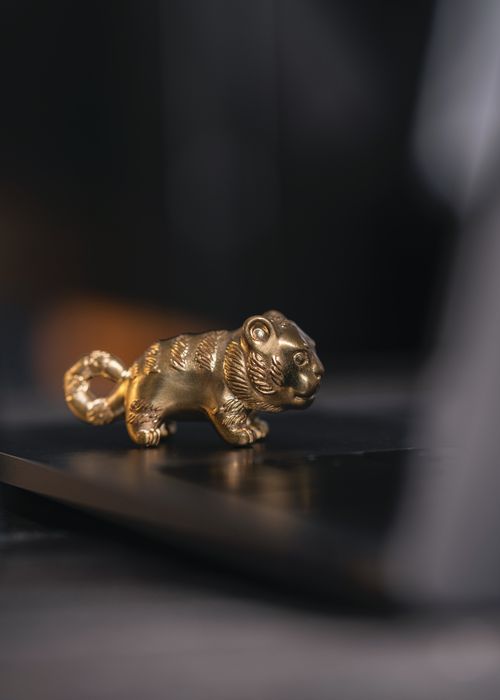 Free Close-up of a gold tiger figurine placed on a sleek black desk surface, adding an elegant touch. Stock Photo