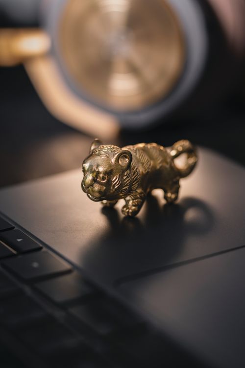 Free Close-up of a brass tiger figurine on a laptop, showcasing a modern and vintage blend. Stock Photo