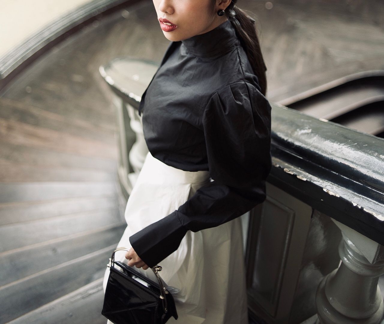 elegant woman in vintage attire stands stylishly on a classic spiral s
