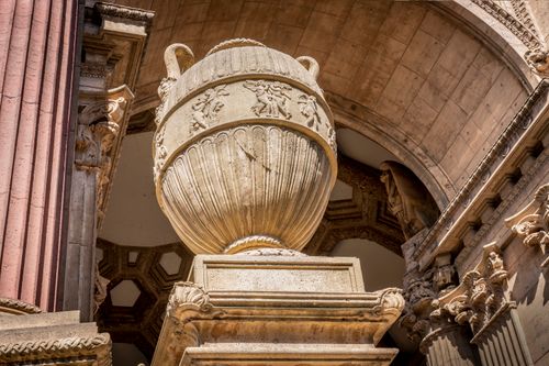 Free Ancient stone vase beneath an ornate classical archway with detailed carvings. Stock Photo