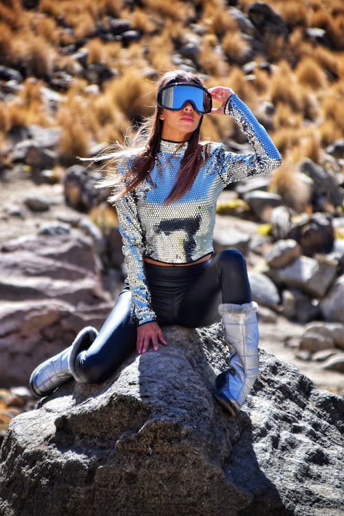 A Woman in Glitter Clothing Posing on a Rock
