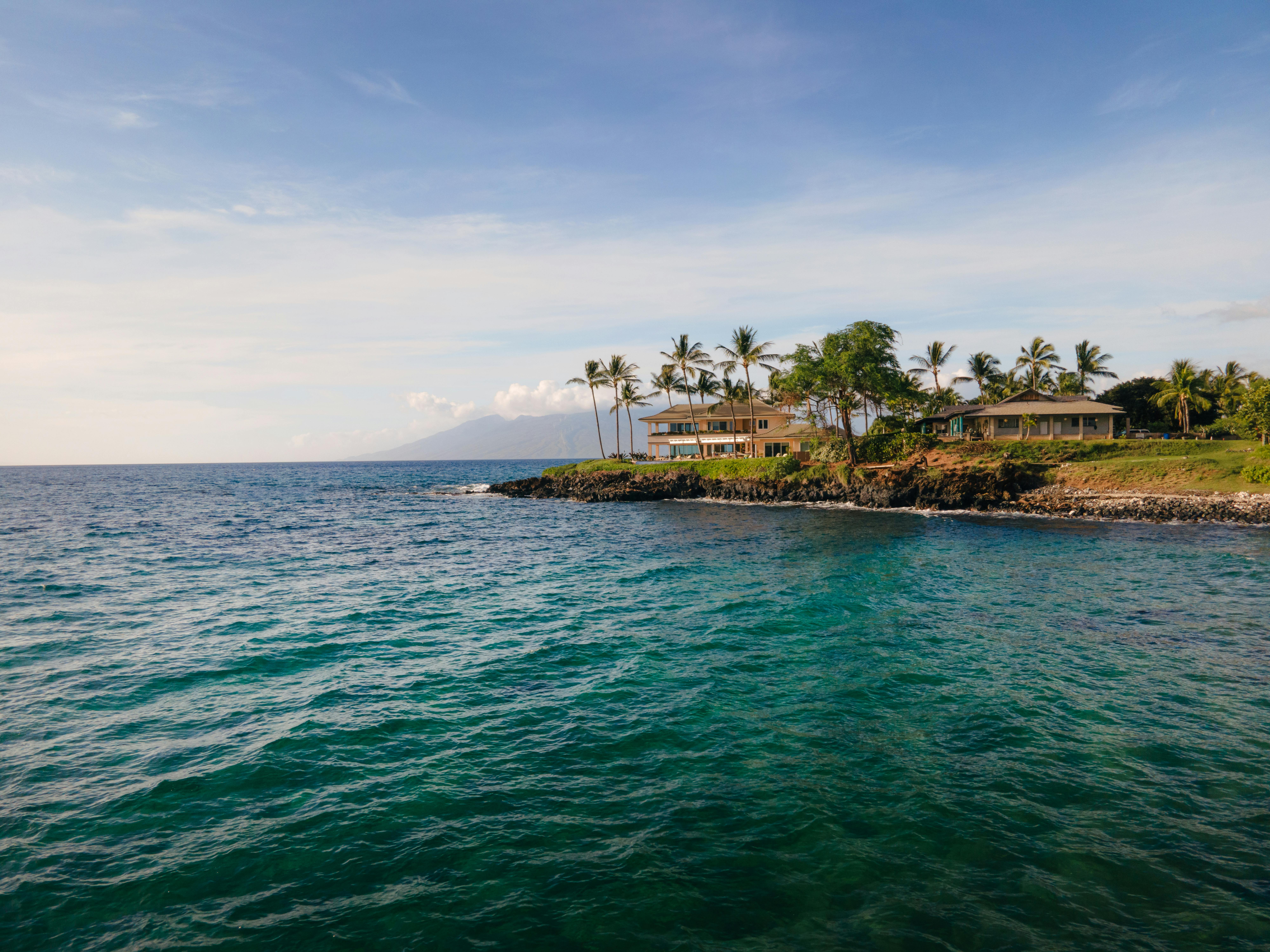 Beautiful oceanfront homes surrounded by palm trees on the coast of Kihei, Maui.