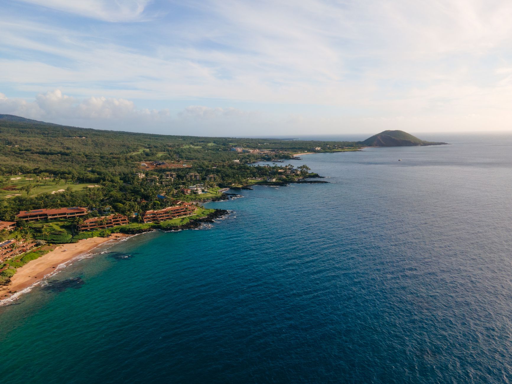 Stunning aerial view of the lush Wailea-Makena coastline in Maui, Hawaii with clear blue ocean waters.