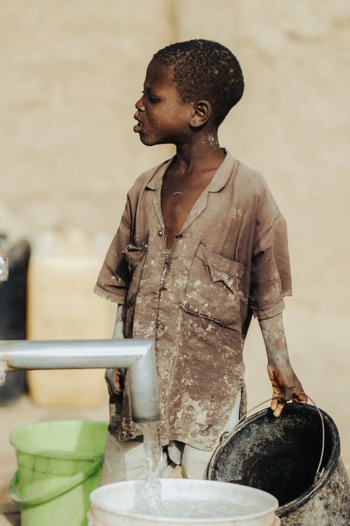 Free A young boy in Chadi, India, collects water from a faucet, highlighting poverty and water scarcity issues. Stock Photo