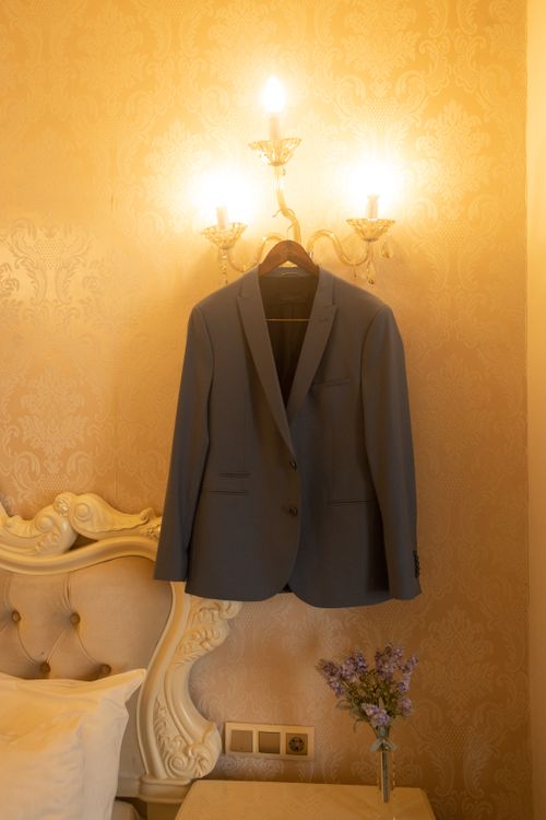 Free A sophisticated suit hangs on a luxurious lamp in a Milan hotel room, exuding elegance and style. Stock Photo