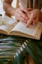 Woman Wearing a Book with a Girl while Sitting at a Table with Palm Leaves