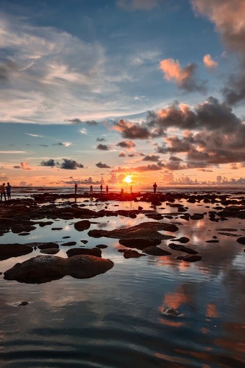 Tourists on a Rocky Beach at High Tide Watching the Sunset