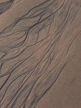 Intricate abstract patterns etched in sand on a GA beach in India.