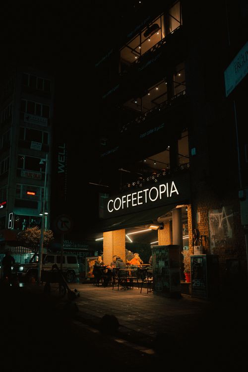 Free Coffeetopia café illuminated at night showcasing urban nightlife ambiance. Stock Photo