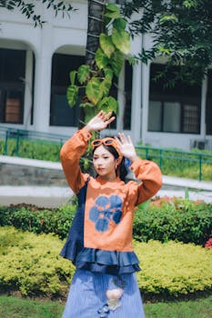 Young woman in vibrant traditional attire posing in a lush garden setting in Bandung, Indonesia.