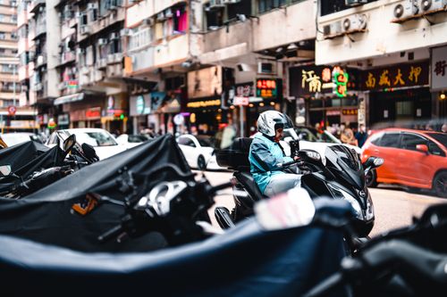 Free Motorcyclist on a busy urban street with colorful signage and heavy traffic. Stock Photo
