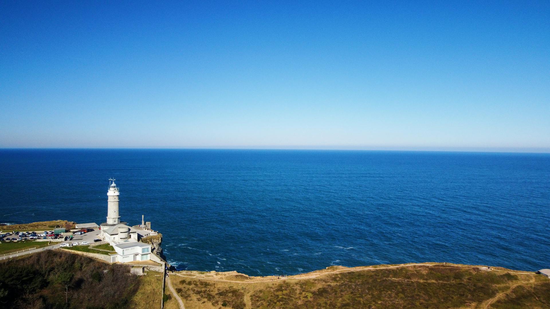 Scenic view of the Santander lighthouse by the ocean under a clear blue sky.