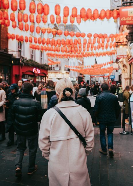 A vibrant scene of people walking under red lanterns in London's Chinatown.