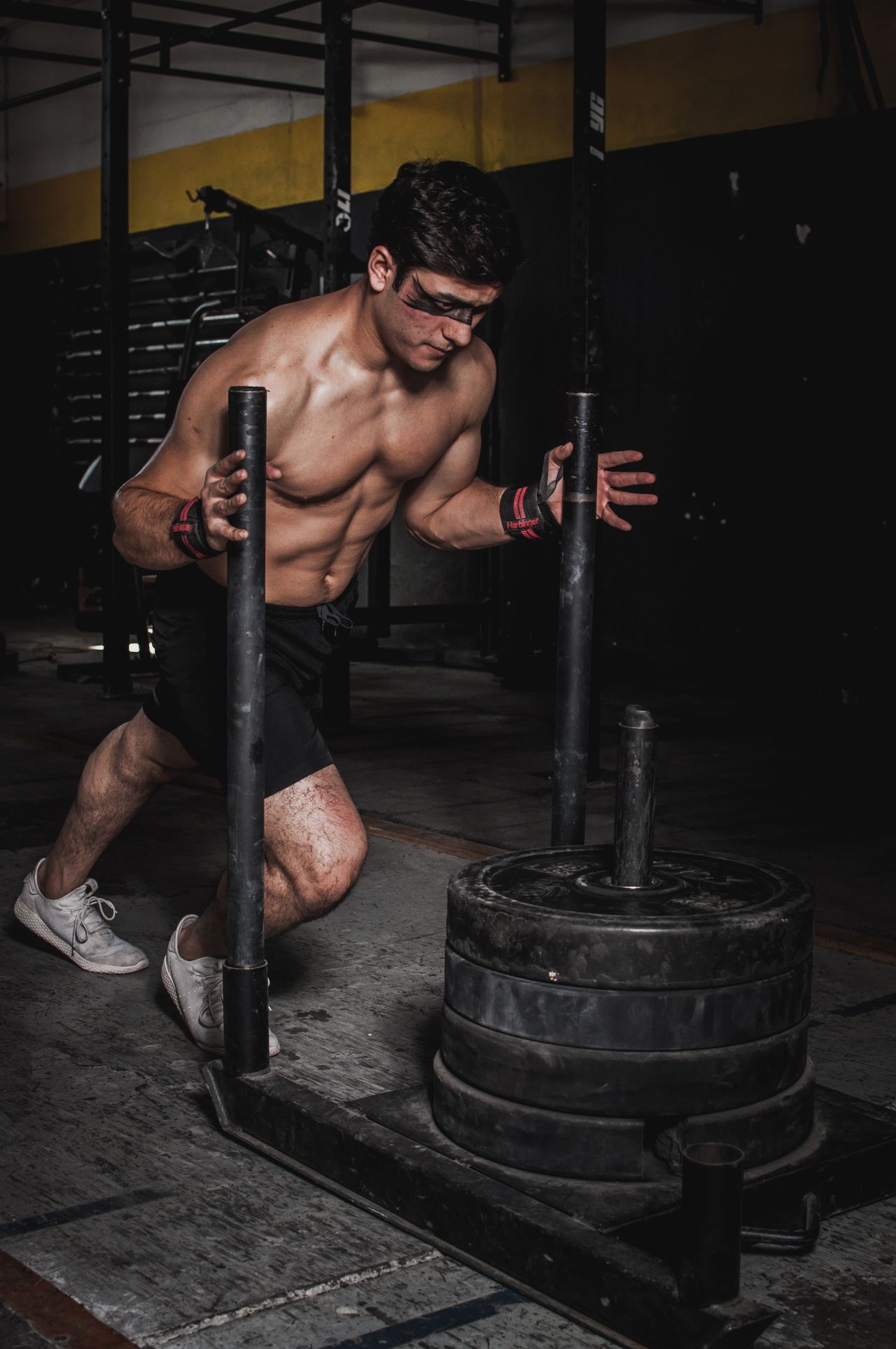 A muscular man pushes a weighted sled in an indoor gym
