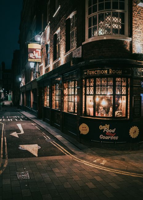 A cozy London pub glows warmly at night on a street corner, capturing the essence of British nightlife.