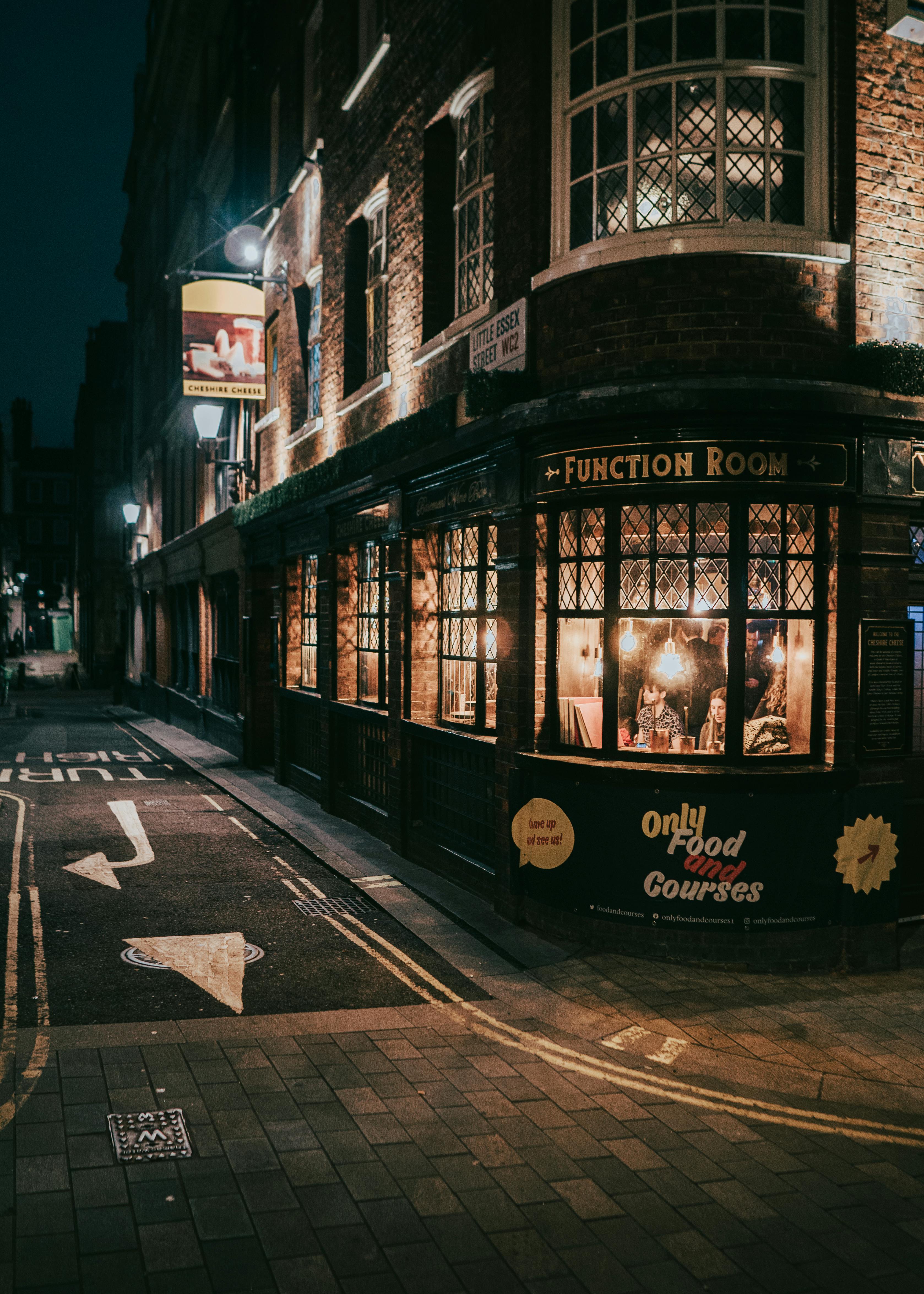 Free A cozy London pub glows warmly at night on a street corner, capturing the essence of British nightlife. Stock Photo
