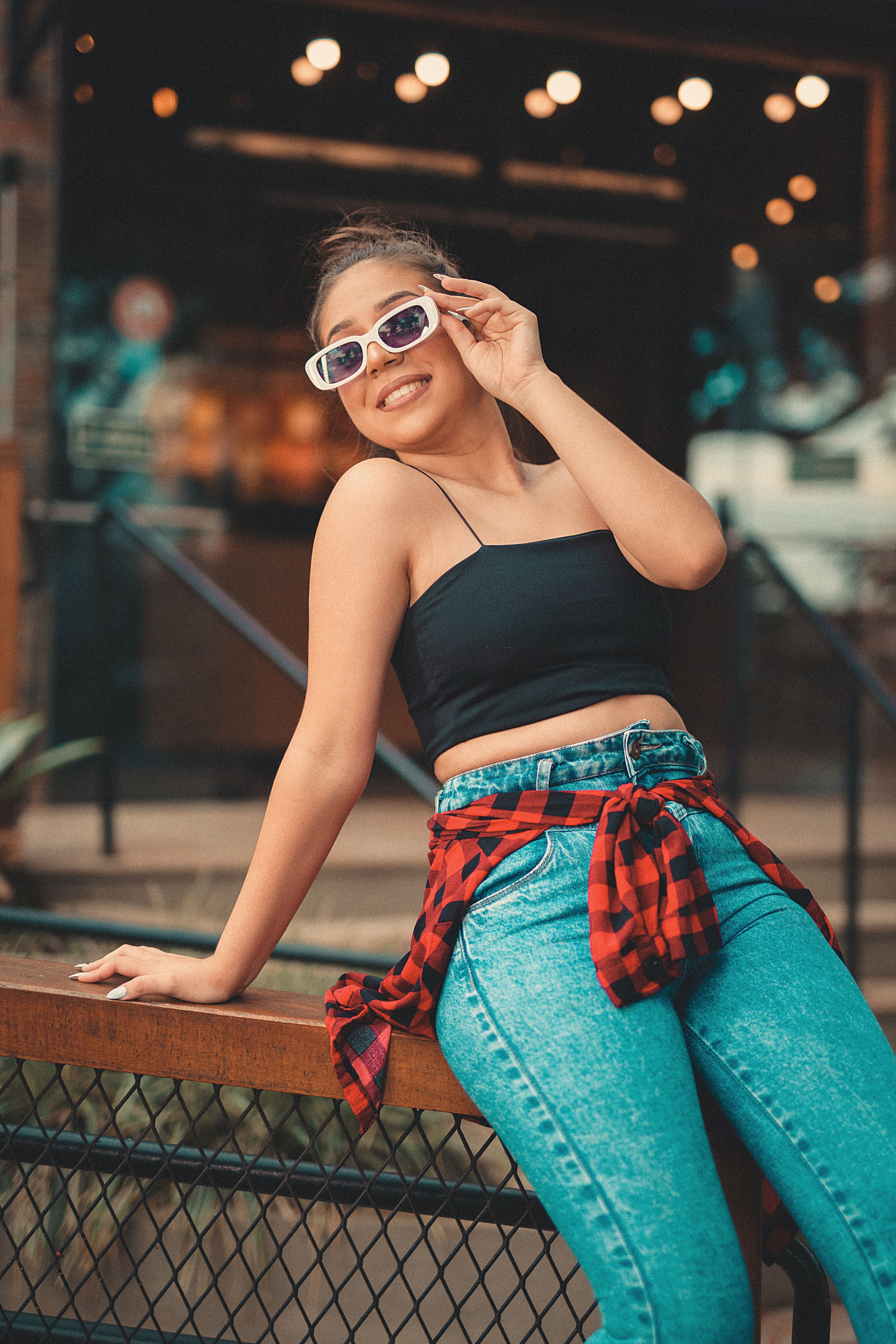 Young Woman in Black Tank Top and Jeans Sitting on a Fence · Free Stock ...