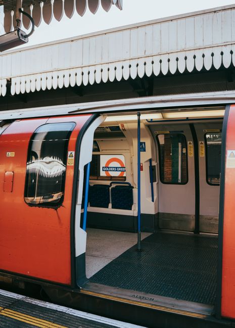 A red London Underground train with open doors at Golders Green station, showcasing urban transport.