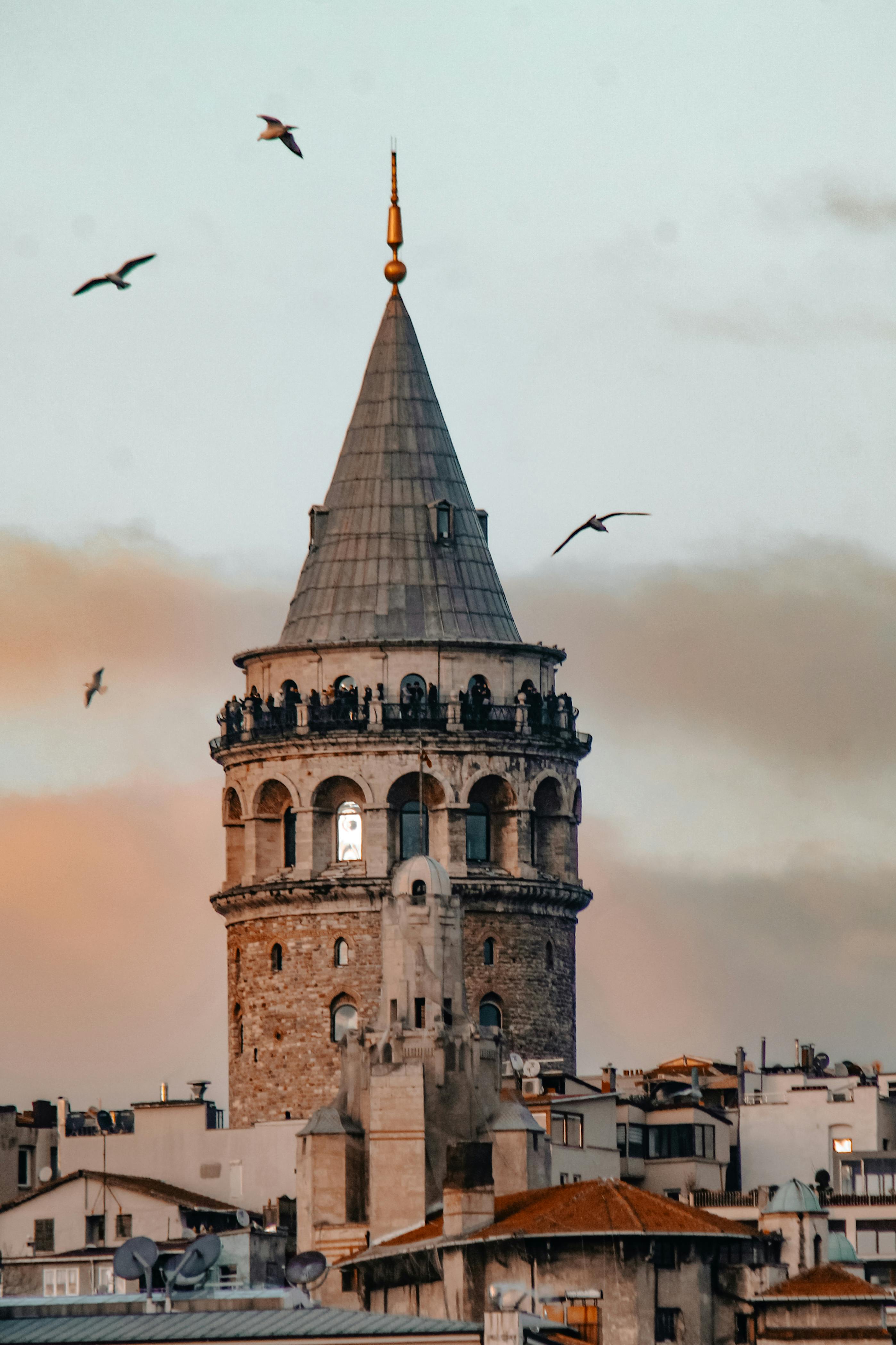 A picturesque view of the historic Galata Tower with birds flying around during sunset in Istanbul, Turkey.