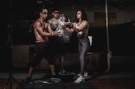 三名穿着运动服的成年人在健身房里用粉笔做准备，即将进行剧烈运动