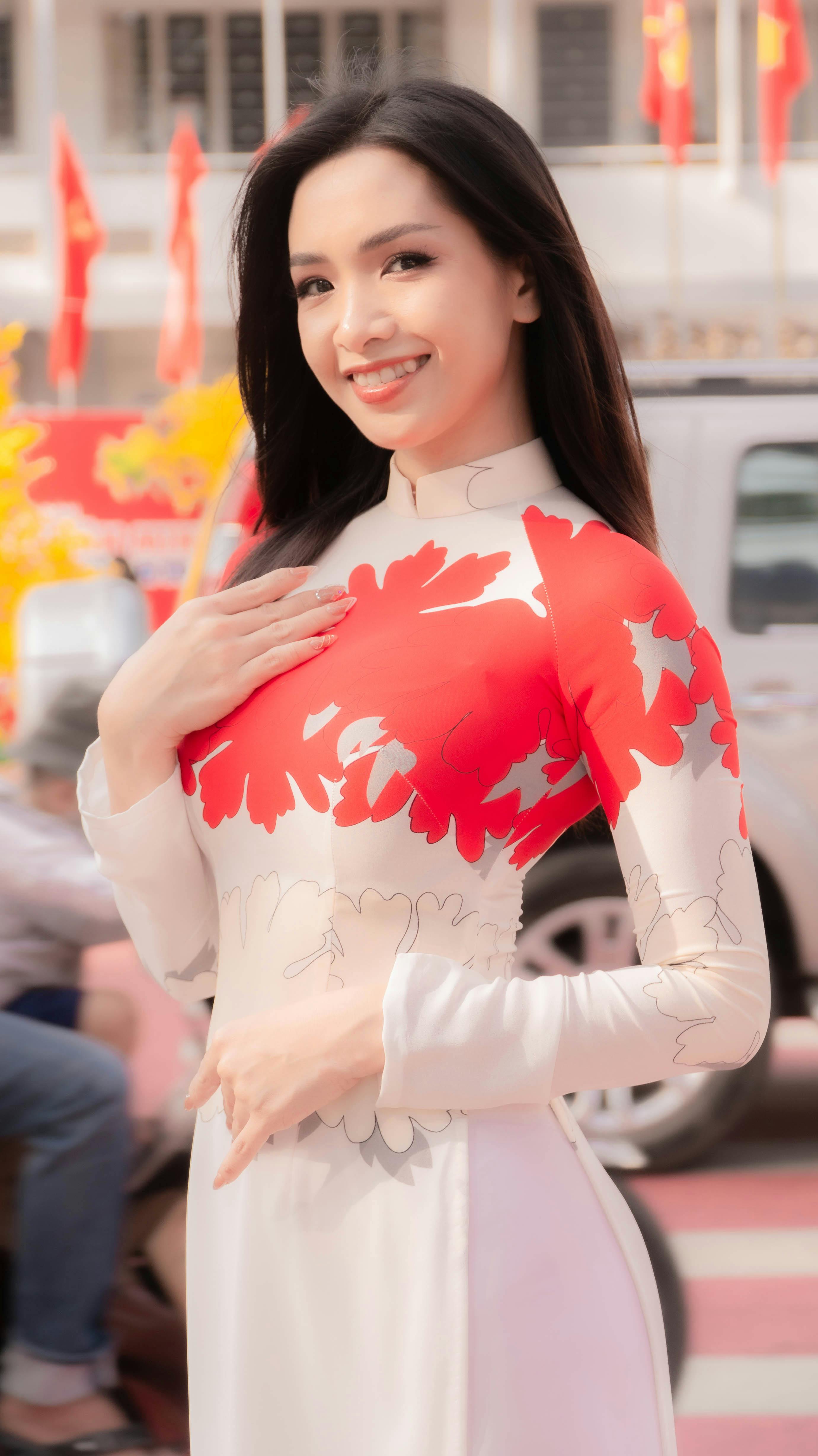 A beautiful young woman in traditional Asian dress poses outdoors, radiating elegance and joy.