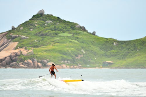 Man in Black Shorts Surfing Under Blue Sky during Daytime