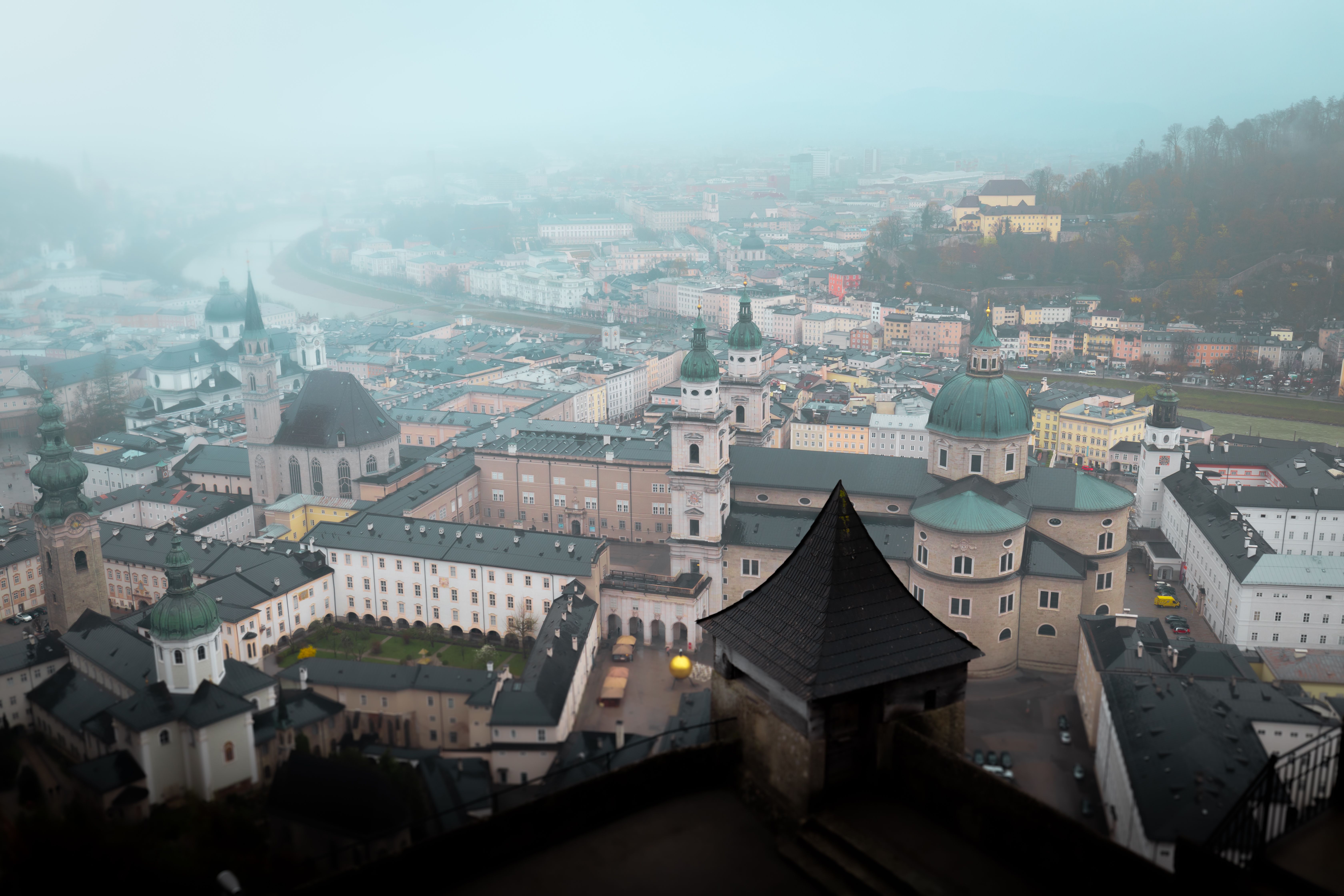 Aerial view of Salzburg, Austria enveloped in fog, showcasing historic architecture.