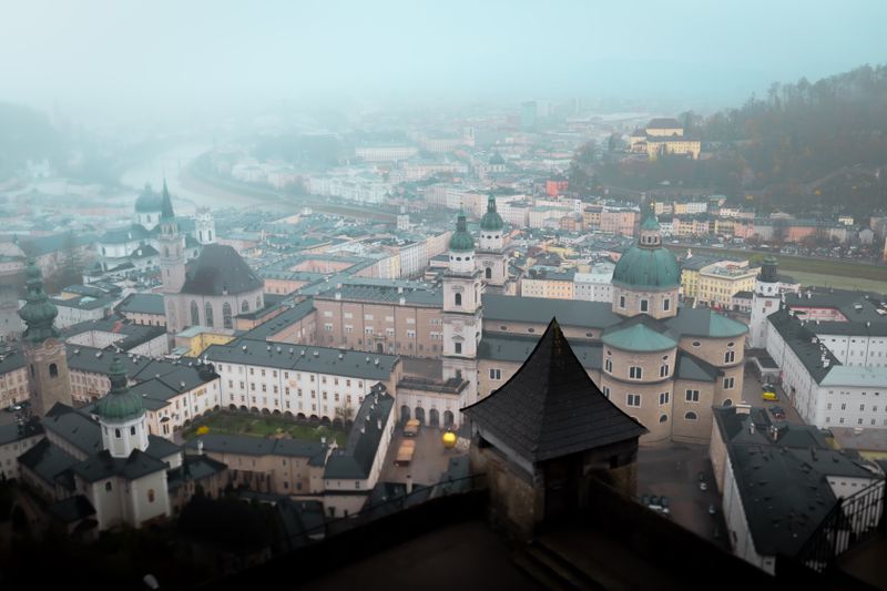 Aerial view of Salzburg, Austria enveloped in fog, showcasing historic architecture.