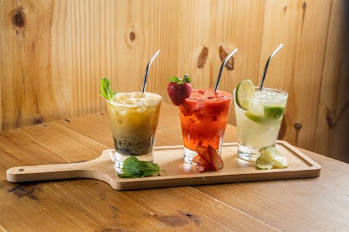 A wooden tray with three drinks on it