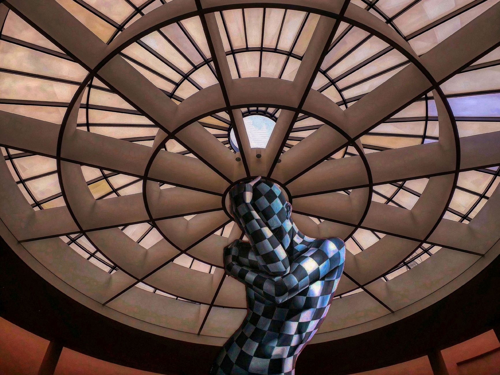 A striking view of modern architecture featuring a geometric statue beneath a detailed dome.