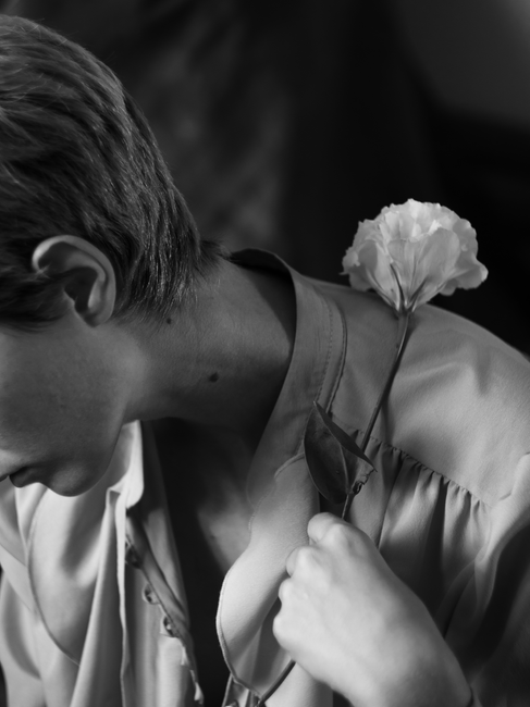 A stylish black and white portrait of a woman holding a flower by her neck.