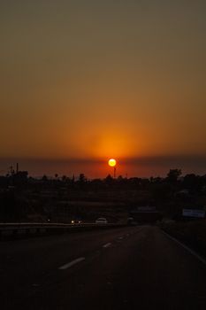Beautiful sunset view over a highway with car silhouettes along multiple lanes.