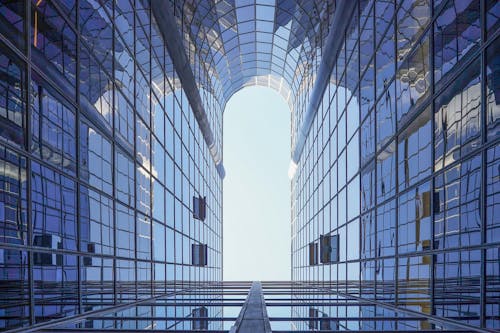 Office buildings, modern glass skyscrapers silhouettes. Bottom view through a modern tall skyscraper up to the blue sky