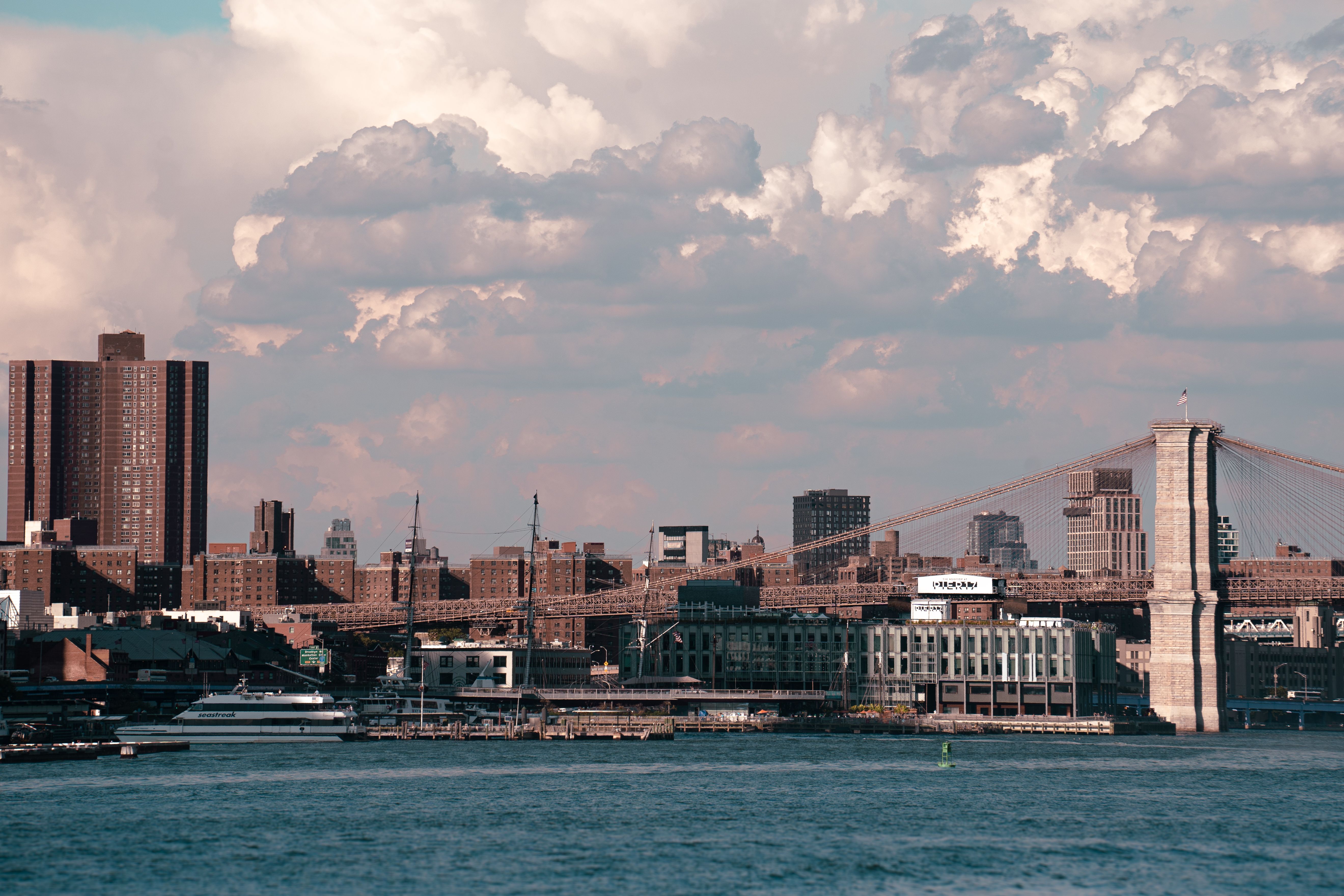Captivating view of Brooklyn Bridge and Manhattan skyline under dramatic clouds.