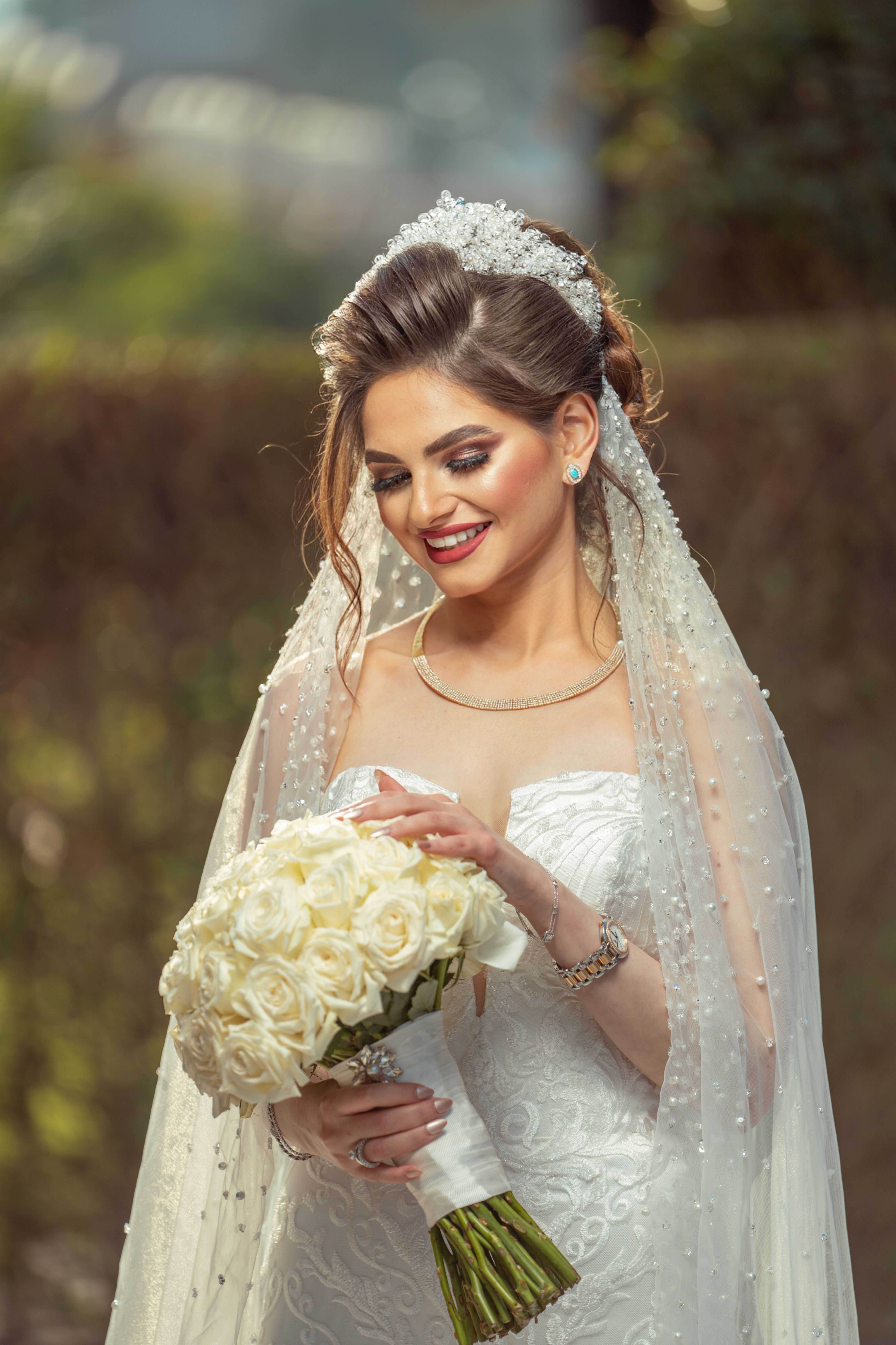 Elegant bride in a wedding dress holding a bouquet outdoors in Iraq.