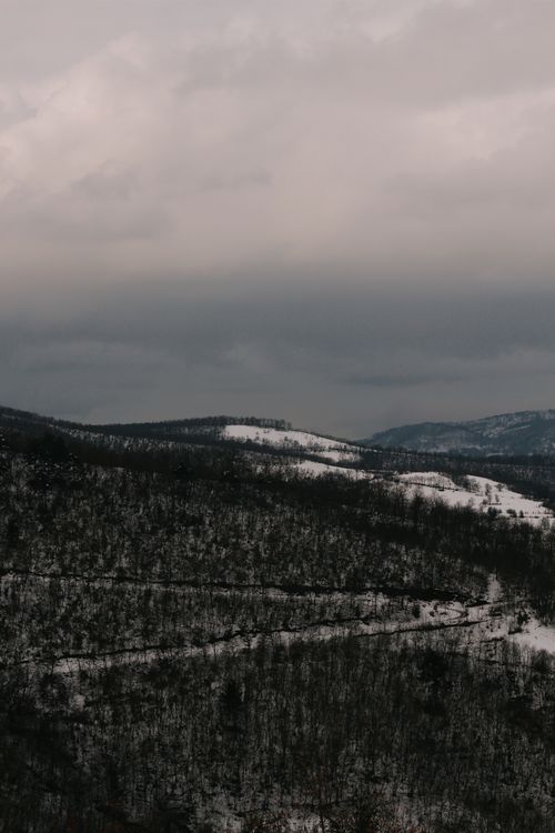 Free Experience the serene beauty of snow-covered mountains under a gloomy winter sky. Stock Photo