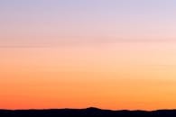 日落宁静，色彩鲜艳，映衬着山脉的轮廓