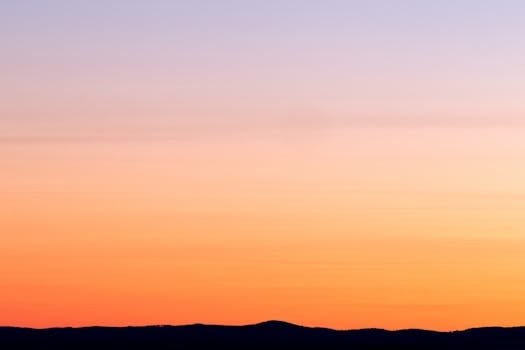 日落宁静，色彩鲜艳，映衬着山脉的轮廓