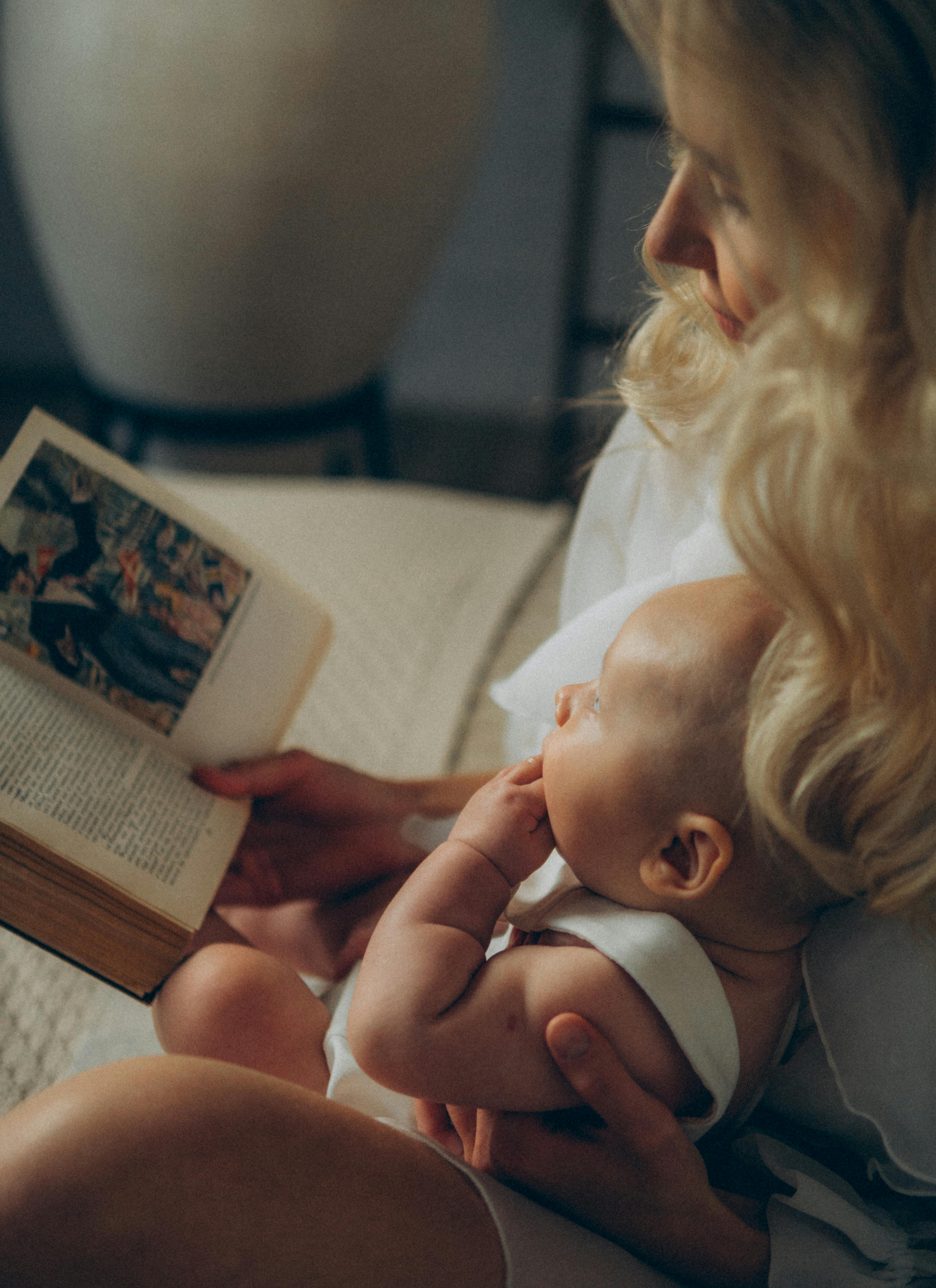 photo of a woman reading a book to a baby