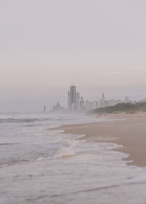 Free A tranquil Gold Coast beach scene with waves and the city skyline at sunrise. Stock Photo