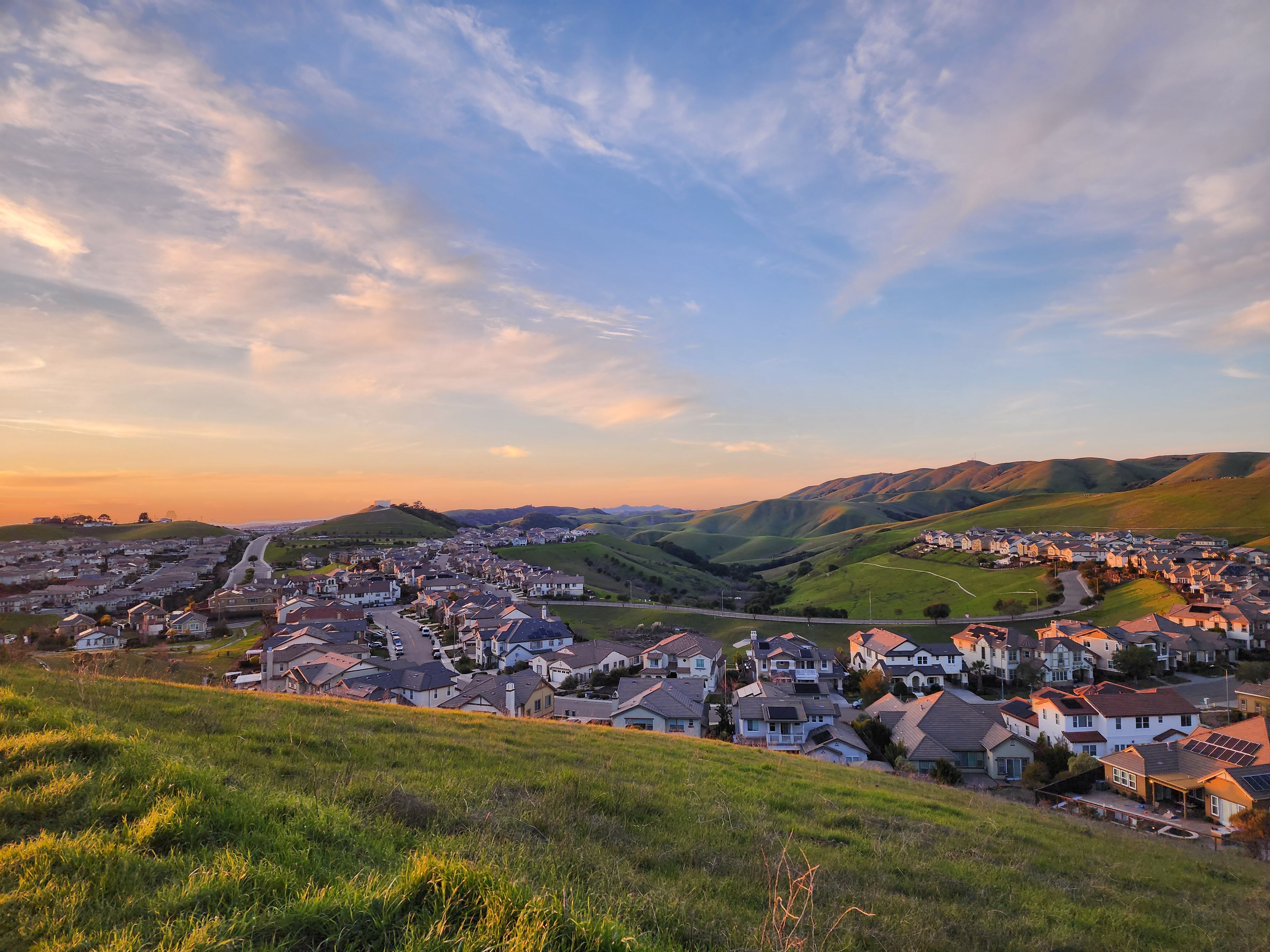 Picturesque village surrounded by green hills at sunset, showcasing serene countryside beauty.