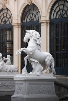 Elegant white horse statue in front of the historic Belvedere Palace in Vienna, Austria.