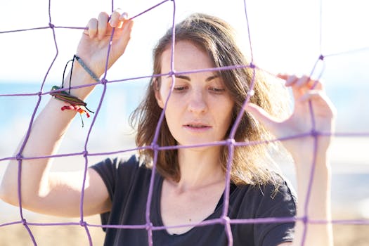 Portrait of a woman holding a purple volleyball net outdoors, showcasing contemplative expression.