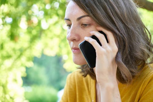 Selective Focus Photography of Woman Holding Smartphone on Her Left Ear