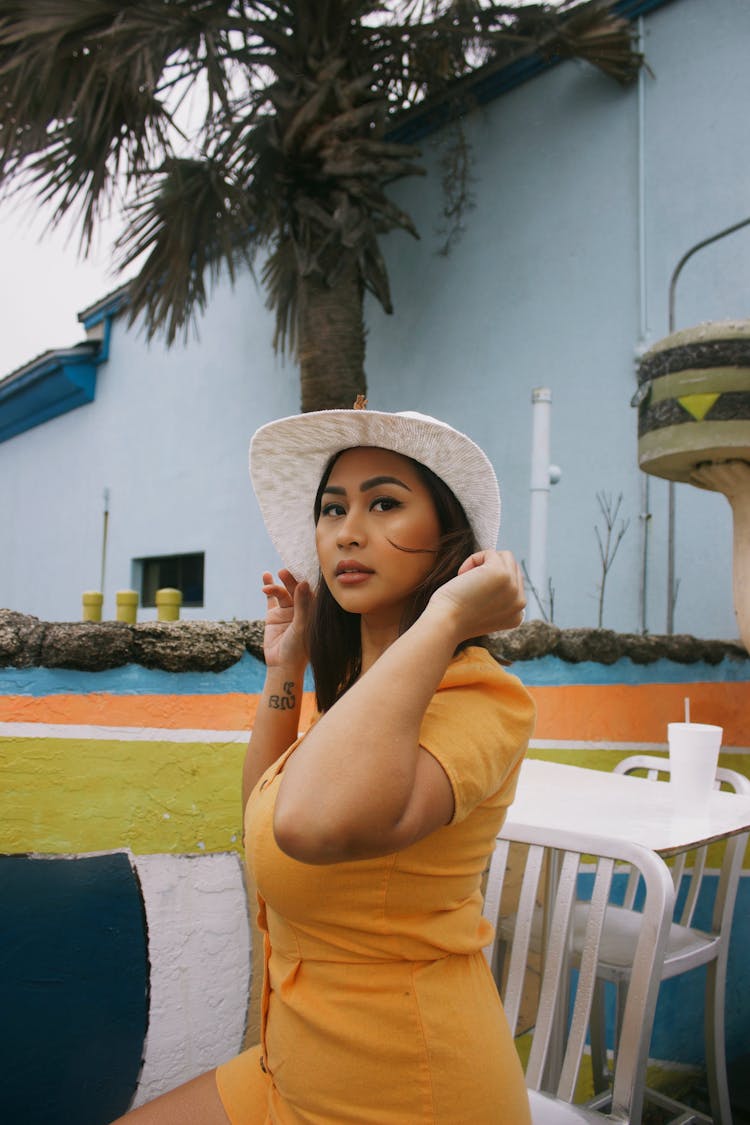 Woman In Hat Sitting On Cafe Outdoor Terrace