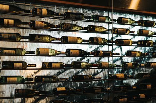 Free Artistic display of wine bottles on a glass wall. Ideal for wine shop themes. Stock Photo